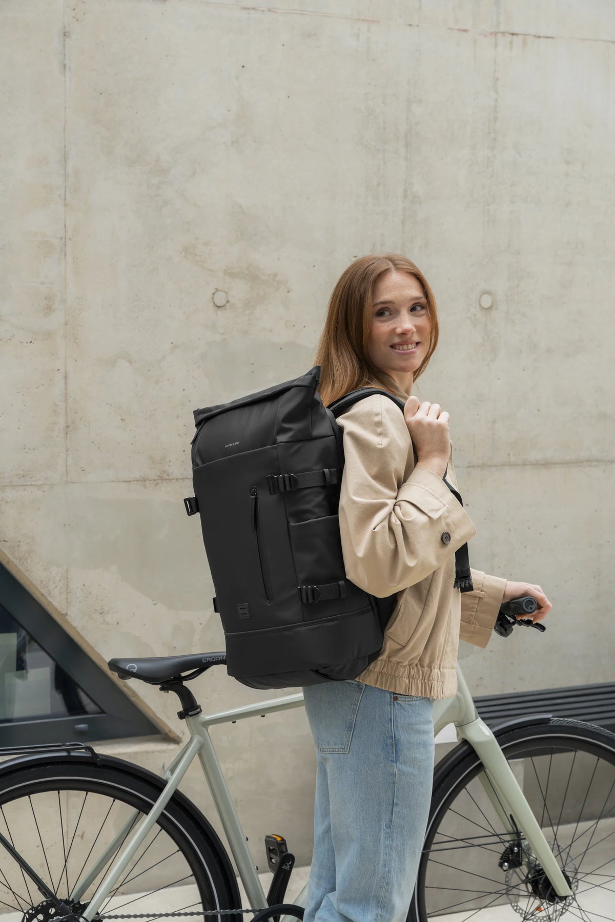 Woman wearing the black bag as a backpack next to her bike