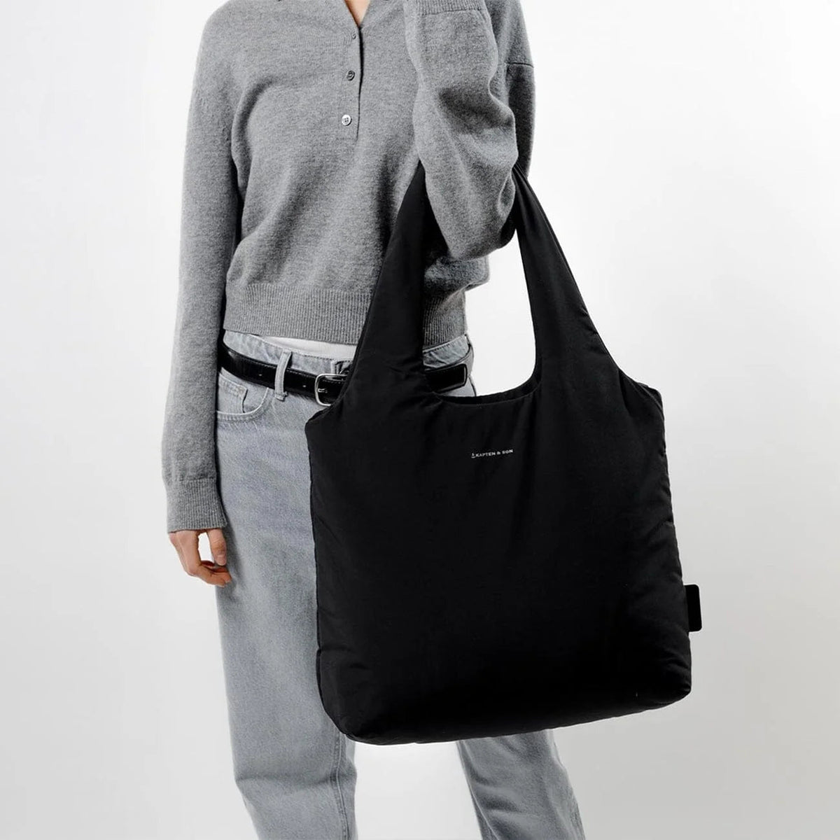 Woman carrying the black tote on her arm by the handles