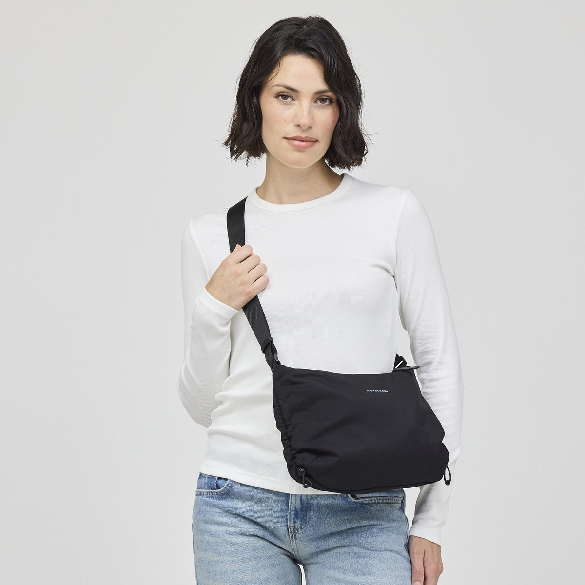 Woman wearing the black Skara Small as a crossbody, front view with the strap adjusted short